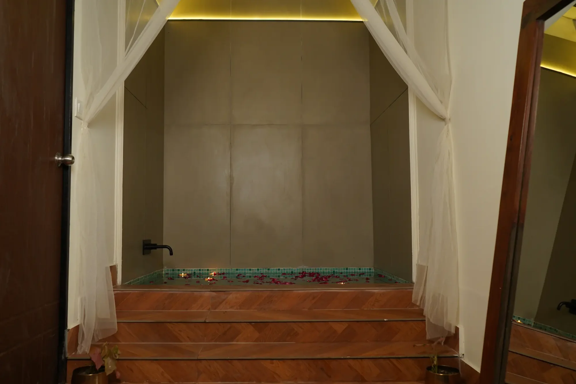Curtained steps leading to an indoor bath