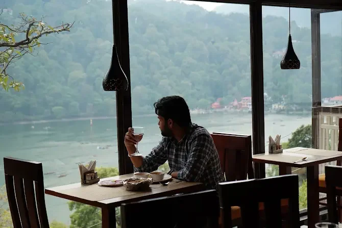 A guest enjoying a drink beside the lake-facing windows