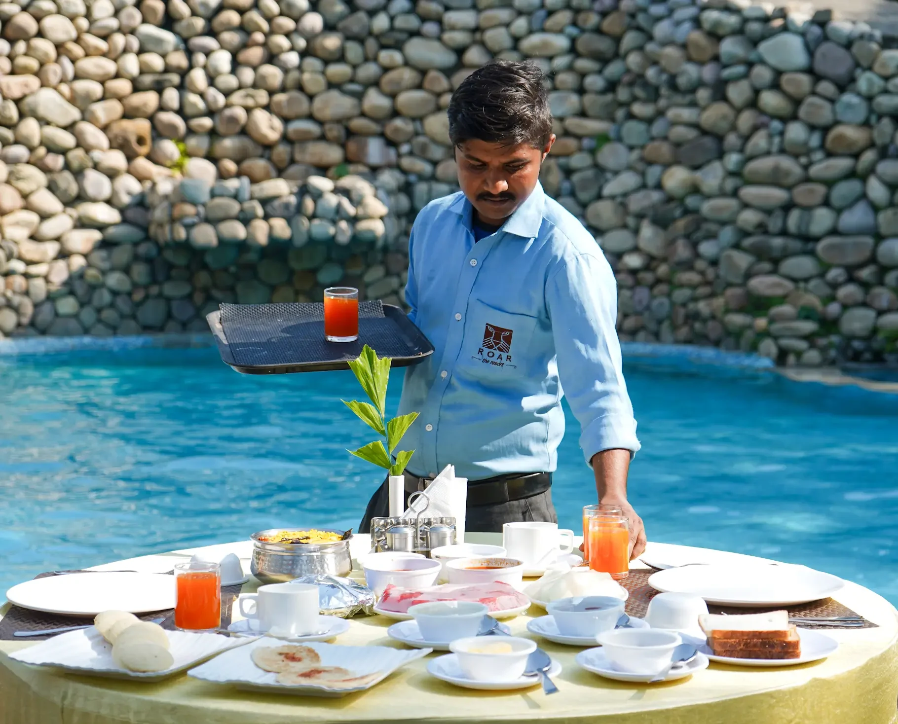 A staff member serving breakfast beside the pool